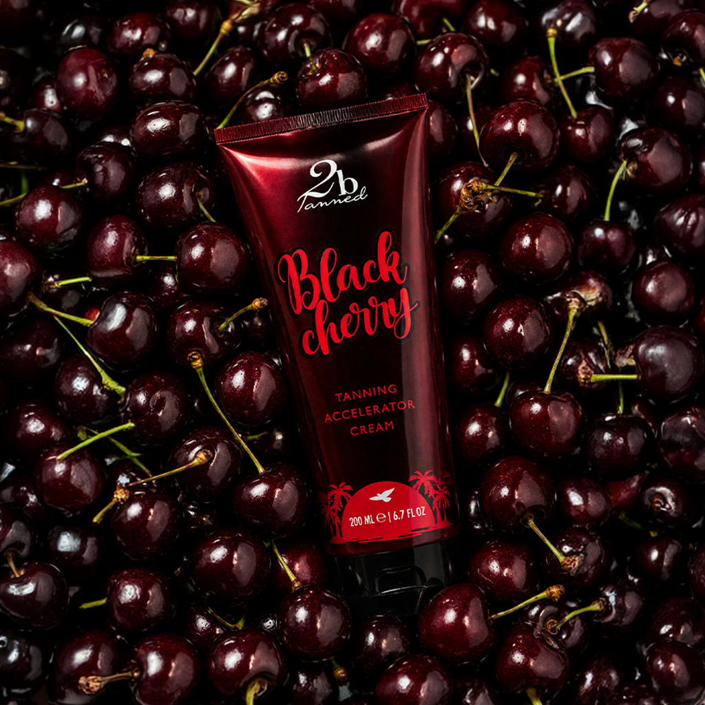 2BTanned Black Cherry Tanning Accelerator Cream on bed of fresh cherries – cherry scented tanning lotion
